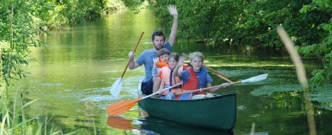 Eine Gruppe paddelt im Kanu den Fluss hinunter.